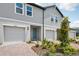 Two-story townhome featuring individual garages, manicured landscaping, and a pop of color at the front door at 16466 Bird Of Paradise Ave, Clermont, FL 34714