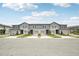Row of townhomes with gray siding, individual garages, and well-maintained landscaping at 16466 Bird Of Paradise Ave, Clermont, FL 34714