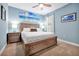 Bedroom featuring a wooden bed frame, bedside tables with lamps and blue walls adorned with beach-themed artwork at 16527 Sea Glass St, Winter Garden, FL 34787