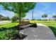 Community bench nestled amongst trees and landscaping providing a tranquil spot to relax and enjoy the outdoors at 16527 Sea Glass St, Winter Garden, FL 34787