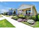 Inviting single-Gathering home showcases a landscaped front yard with flowering shrubs, a cozy porch with a bench, and a two-car garage at 16527 Sea Glass St, Winter Garden, FL 34787