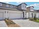 A townhome's exterior shows a two-car garage, stylish lighting, and a paved driveway with fresh landscaping at 1801 Archer Dr, Minneola, FL 34715