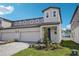 Exterior elevation showcasing a modern two-story townhome with a two-car garage and landscaped front yard at 1801 Archer Dr, Minneola, FL 34715
