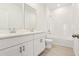 Well-lit bathroom with double vanity, white cabinets, and a combined tub and shower at 1812 Archer Dr, Minneola, FL 34715