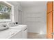A well-lit laundry room featuring modern washer and dryer units, wire shelving, and a window at 2028 Sussex Rd, Winter Park, FL 32792