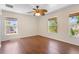 Bright, empty bedroom with hardwood floors, ceiling fan and natural light from three windows at 2260 The Oaks Blvd, Kissimmee, FL 34746
