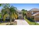 Two-story home featuring a well-manicured lawn and mature palm trees at 2260 The Oaks Blvd, Kissimmee, FL 34746