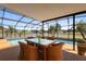 Covered lanai with table and chairs overlooking a beautiful pool and waterfront view at 2260 The Oaks Blvd, Kissimmee, FL 34746