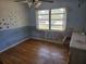 Spacious bedroom with hardwood floors, blue accent wall, and bright window at 2523 Falkner Rd, Orlando, FL 32810