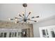 Modern chandelier adds a unique touch to the living space with stone fireplace and natural light at 2525 Venetian Way, Winter Park, FL 32789