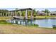 Picturesque view of the pond featuring a covered dock with a walking bridge, surrounded by lush greenery at 2680 Nottel Dr, St Cloud, FL 34772
