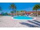 Luxurious community pool surrounded by palm trees, umbrellas, and lounge chairs on a sunny day at 2718 Bushman Dr, Kissimmee, FL 34746