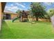 Spacious backyard featuring a wooden playset, lush green lawn, and a privacy fence at 2739 Village Pine Ter, Orlando, FL 32833