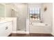 Sleek bathroom featuring glass shower and soaking tub with a window, surrounded by neutral tiling at 2739 Village Pine Ter, Orlando, FL 32833