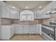 Modern kitchen with white cabinetry, tiled backsplash, and stainless steel appliances, showcasing style and convenience at 312 Grand Bay Ln, Celebration, FL 34747