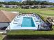 Aerial view of a pool with several lounge chairs and tables surrounded by a white fence and green bushes at 367 Par Pines Blvd, Davenport, FL 33837