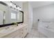 Bright bathroom with double sinks, a tub, and a large mirror at 4544 Point Look Out Rd, Orlando, FL 32808