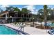 An eye-level pool-side view of the community building, lush landscaping, and comfy lounge chairs at 551 Pine Needle Ct, Lake Mary, FL 32746