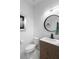 Stylish half-bathroom featuring a modern vanity with wood accents, a round mirror, and sleek black fixtures at 5511 Orange Orchard Dr, Winter Garden, FL 34787