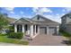 Attractive single-story home featuring a brick driveway, a covered porch, and an attached two-car garage at 5511 Orange Orchard Dr, Winter Garden, FL 34787