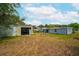 Spacious backyard with a detached shed, lush lawn, and adjacent single-story home with blue siding at 55119 5Th St, Astor, FL 32102