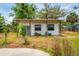 Shows the exterior of the home with a small porch and an overgrown yard at 55119 5Th St, Astor, FL 32102