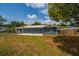 Single-story home with blue siding and a concrete patio, surrounded by well-kept grass and mature trees at 55119 5Th St, Astor, FL 32102