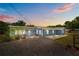 Charming single-story home with gravel driveway, blue siding, and a peaceful residential setting at dusk at 55119 5Th St, Astor, FL 32102