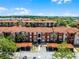 Elevated view of an apartment complex with red tiled roofs surrounded by lush trees and landscaping at 5530 Metrowest Blvd # 309, Orlando, FL 32811
