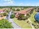 Aerial view of an apartment complex with red tile roofs, landscaping, a lake, and parking at 5530 Metrowest Blvd # 309, Orlando, FL 32811