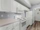 Well-lit kitchen with white appliances and cabinets, including a microwave and range at 5530 Metrowest Blvd # 309, Orlando, FL 32811