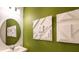 Bathroom with a green wall, modern art, round mirror, and a white sink at 5657 Loggia Ln, Kissimmee, FL 34758