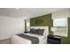 Bright bedroom featuring a green accent wall, two windows, and minimalist decor at 5657 Loggia Ln, Kissimmee, FL 34758