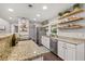 Bright kitchen featuring granite countertops, stainless appliances, and floating wood shelves at 694 Tuscora Dr, Winter Springs, FL 32708