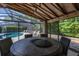 Screened patio boasts a large stone table with firepit, alongside views of the pool and backyard at 694 Tuscora Dr, Winter Springs, FL 32708
