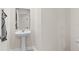 Stylish powder room featuring modern pedestal sink and elegant mirror, exuding minimalist charm at 740 Simone Ct, Haines City, FL 33844