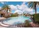 Community pool surrounded by palm trees, lush landscaping, and comfortable seating, perfect for leisure at 7505 Pellham Way, Kissimmee, FL 34747