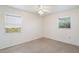 A bright bedroom with neutral walls, carpet flooring, and natural light from two windows at 7700 Grevillea Dr, Orlando, FL 32822