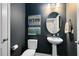 Stylish powder room with dark paint, a pedestal sink, and decorative wall art at 8263 Bellow St, Orlando, FL 32827
