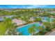 Aerial view of the long community pool with palm trees, lounge chairs, beach volleyball court and buildings in distance at 8263 Bellow St, Orlando, FL 32827