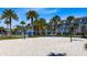Community sand volleyball court surrounded by palm trees and blue skies at 8263 Bellow St, Orlando, FL 32827