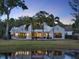 Picturesque backyard with mature palm trees overlooking a pond, lush landscaping, and an outdoor kitchen at 9364 Thurloe Pl, Orlando, FL 32827