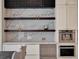 Custom built-in bar with open shelving, white cabinets, and quartz backsplash in kitchen at 9364 Thurloe Pl, Orlando, FL 32827