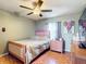 Cozy bedroom featuring a ceiling fan, light green walls, and wood-look tile flooring at 1072 Se 155Th St, Summerfield, FL 34491