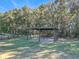 A metal carport with a gravel base, located on a grassy area next to a black fence and trees at 1072 Se 155Th St, Summerfield, FL 34491