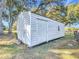 Durable shed with a large door and small window set in a grassy yard beneath mature shade trees at 1072 Se 155Th St, Summerfield, FL 34491