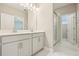 Well-lit bathroom featuring white cabinets, double sinks, glass shower door, and marble tile flooring at 11941 Bracco St, Winter Garden, FL 34787