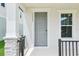 Elegant gray front door framed by white trim and a sidelight, enhanced by stone porch columns at 11941 Bracco St, Winter Garden, FL 34787