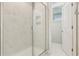 Close up of a stylish glass shower with white marbled tiling and an open doorway at 11941 Bracco St, Winter Garden, FL 34787