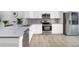 Modern kitchen with stainless steel appliances, white cabinets, and a gray backsplash at 12133 Augusta Woods Cir, Orlando, FL 32824